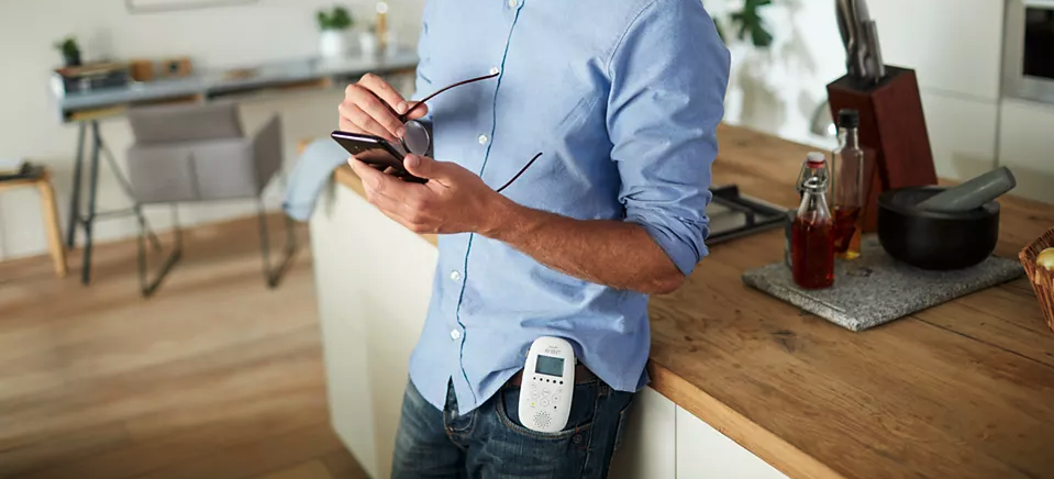 pere qui regarde son telephone avec babyphone clipser a la taille